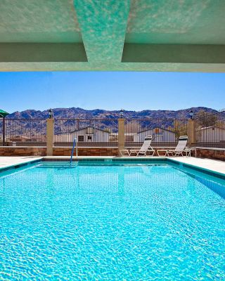 This image shows a refreshing indoor-outdoor pool with lounge chairs and umbrellas in a sunny setting, offering a scenic view of nearby mountains.