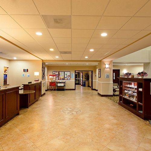 The image shows a hotel lobby with a reception desk, seating area, and a small shop with snacks and drinks.